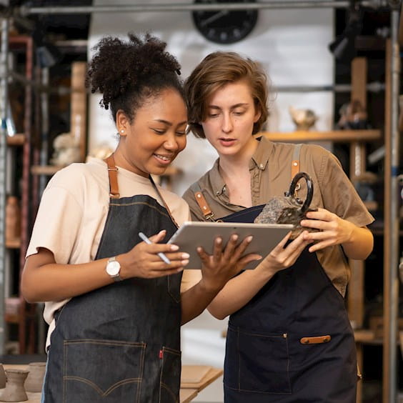 two women checking inventory on an ipad at a small ceramics business