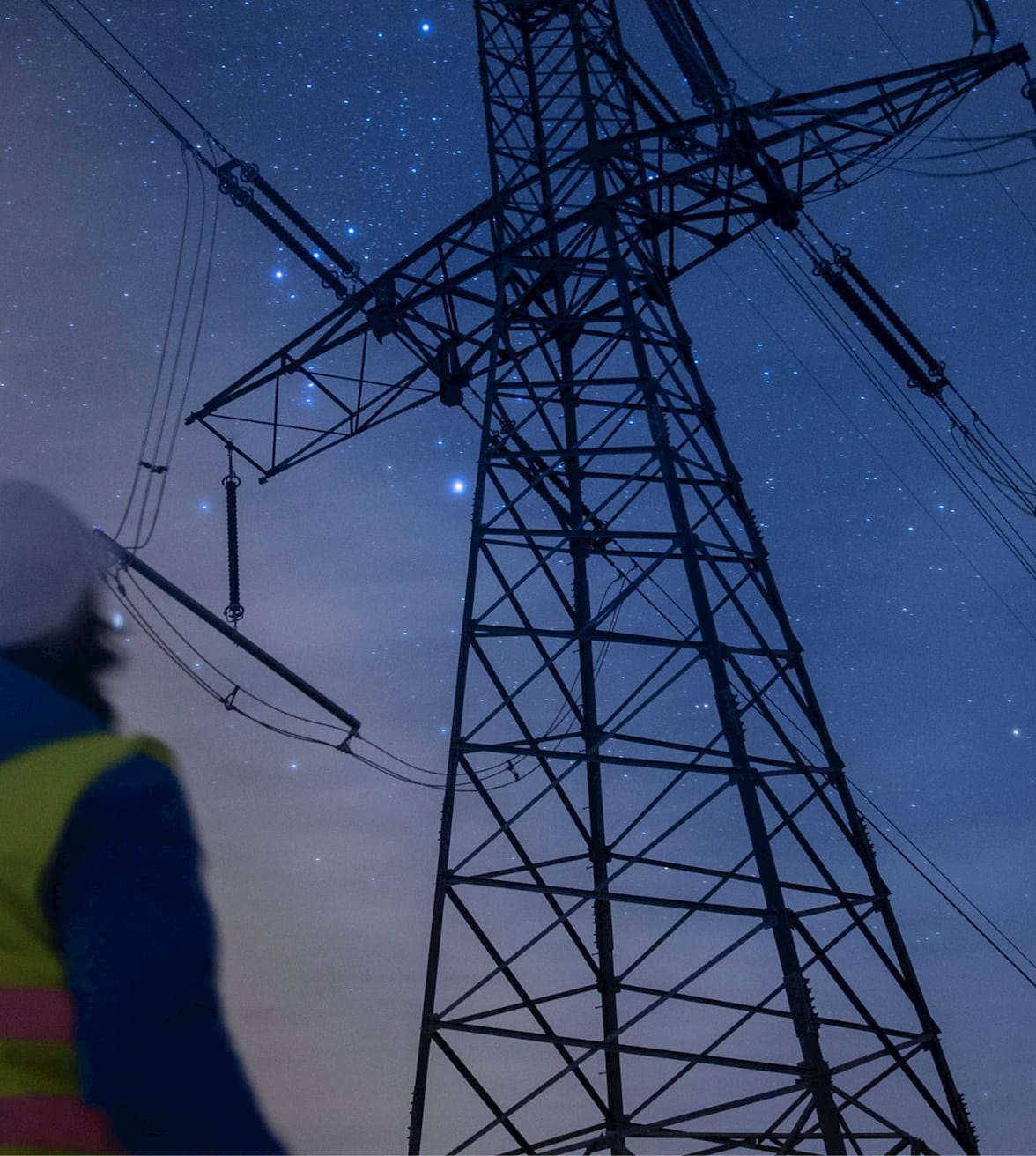 utility worker using a flashlight to examine a utility tower