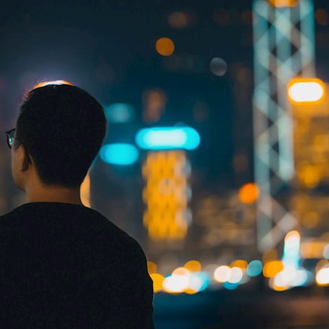 man looking at a city's skyline at night 
