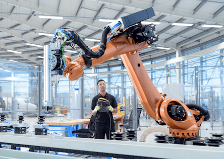 person controlling robot in a manufacturing plant